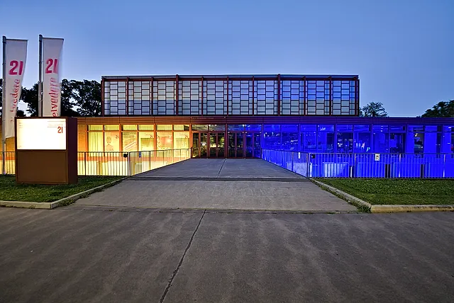 Belvedere 21 at dusk, its glass front lit up in blue